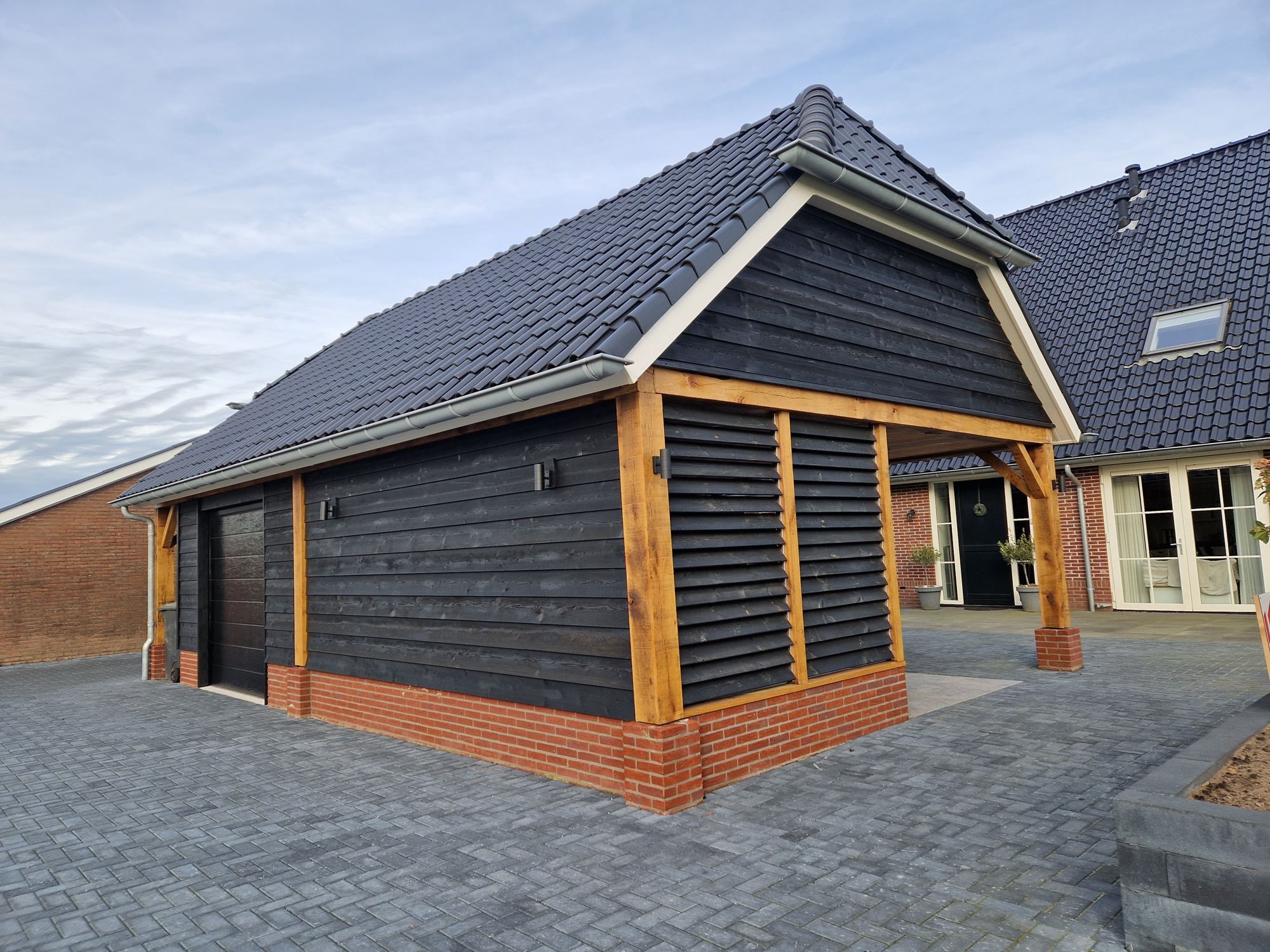 Afgebouwde schuur met puntdak, zwarte houten gevelbekleding en houten staanders