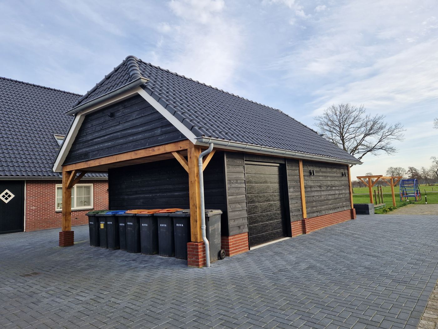 Zijkant van de schuur met roldeur en overkapping