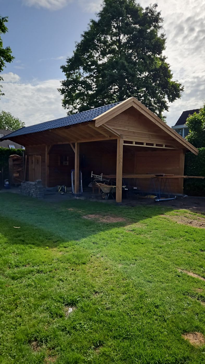 Tuinhuis met nieuwe open overkapping onder een donker dak, nog zonder glazen wanden